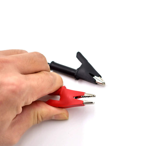 Hand holding Two Pack 4mm Banana Plug To Alligator Clip Test Lead Set 14AWG For Multimeter And Oscilloscope, red and black clips visible