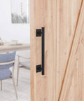 Antique Rustic Twelve And Five Eighths Inch Barn Door Handle installed on wooden door, frosted black finish, square base.