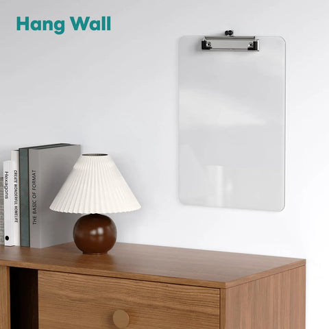 Clear Plastic Clipboard 2 Pack For 8.5 By 11 Papers, Letter Size hangs on wall above a wooden desk with a lamp and books.