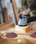 Person using random orbital sander with 5 Inch 8-Hole Sanding Disc Set With Hook And Loop Includes Grits 60 80 100 120 180 240 320 400
