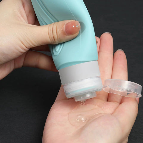 Close-up of a hand using On The Go Travel Bottles For Toiletries Set 5 Pack TSA Approved 3oz Leak Proof Refillable Containers.