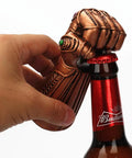 Infinity Gauntlet Bottle Opener Multipurpose Party Tool For Home Use Dope Thanos Style Resin And Metal Construction With Copper Finish Glass Cap Remover Beer And Soda Bottle Topper Gadget For Kitchen And Bar being used on a bottle