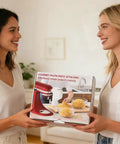 Two people holding a boxed All In One Pasta Press Attachment For Stand Mixers With 7 Interchangeable Plates in kitchen.