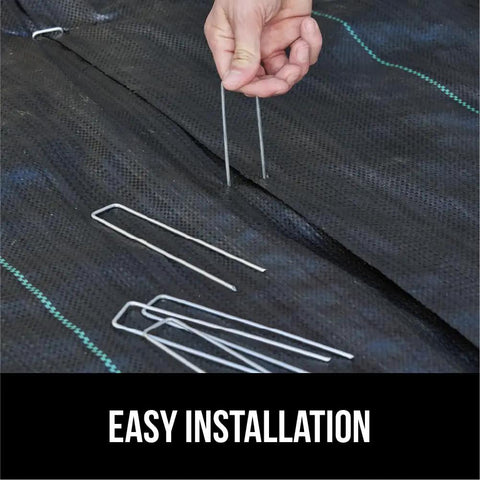 Beefy 6 Inch Landscape Staples 50 Pack 11 Gauge Galvanized Steel Stakes With Ultra Sharp Tip being installed in weed barrier fabric.