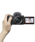 ZV-E10 Mirrorless Camera Kit With 16-50mm Lens in hand, showing flip-out screen with selfie mode.