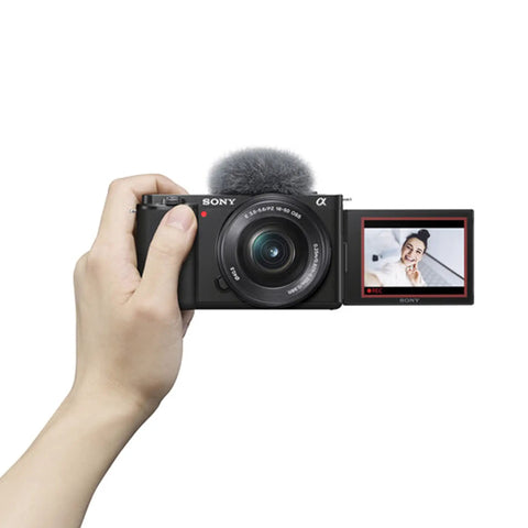 ZV-E10 Mirrorless Camera Kit With 16-50mm Lens in hand, showing flip-out screen with selfie mode.