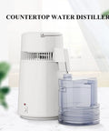 Built Tough Water Distiller Machine Packs 750 Watt Heating Coil with clear four liter catch bucket on countertop.