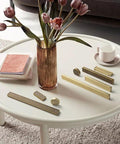 Six Pack Antique Brass Finger Pulls For Cabinets And Drawers displayed on a white table with books, vase, and cup.