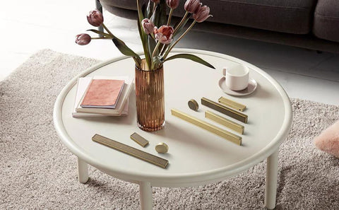 Six Pack Antique Brass Finger Pulls For Cabinets And Drawers displayed on a white table with books, vase, and cup.
