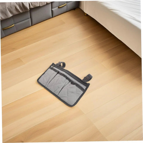 Gray Bed Rail Organizer Bag With Adjustable Strap And Four Storage Pockets lying on wooden floor near bed.