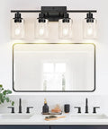 Sleek Matte Black Four Light Bathroom Vanity Wall Lamp With Thick Clear Glass Shades For Mirror Or Porch, mounted above white sink.