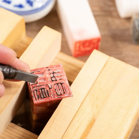 Adjustable Wood Carving Tool Clamp For Engraving And Seal Carving secures red seal block with hand tool in mini bench clamp.