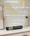 Fanttik Slim V8 APEX car vacuum, black handheld with transparent canister, on shelf beside plugged-in charger.