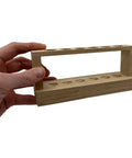 Hand holding Small Wooden Test Tube Rack for six 15mm tubes, 6 inch long, unfinished oak, economy lab rack for compact science setups.