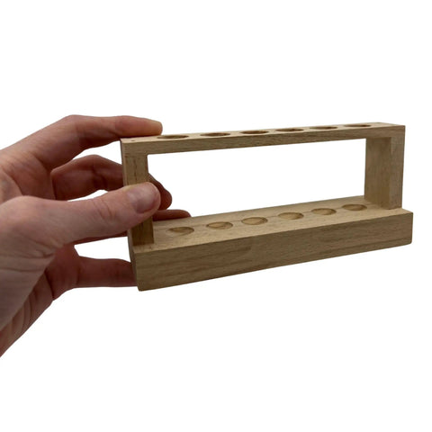 Hand holding Small Wooden Test Tube Rack for six 15mm tubes, 6 inch long, unfinished oak, economy lab rack for compact science setups.