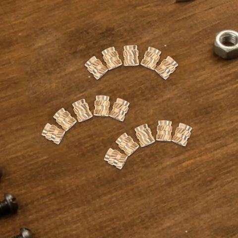 Grab 100 Pack of Solid Copper Heat Set Inserts With Knurled Threads For Heavy Duty Screws Embedment That Stick Like A Champ In Any Project Without Fail arranged on a wooden surface.