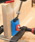 Close-up of Carpentry Locator Jig For 15 Degree Dowel Drilling Kit in action on wood block with drill bit inserted.