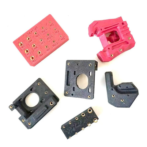 Assorted plastic and 3D-printed parts with inserted brass knurled nuts using a Heavy Duty Heat Press Insertion Tool Kit.
