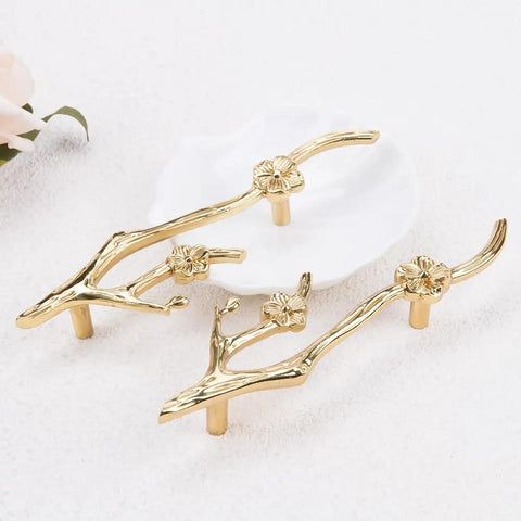 Slick Twig Drawer Pulls In Polished Brass Plum Blossom Branch Handle For Cabinets And Dressers, shown on light surface.