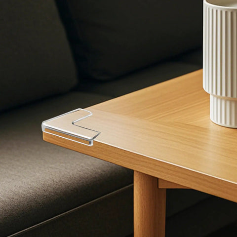 Corner of a wooden table with Eight Piece Silicone Corner Protectors For Baby Proofing And Home Safety Slim Edge Guards on it.
