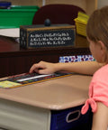 Student using Top Shelf Chalkboard Style K-2 Desk Reference Mats made of premium plastic on classroom desk.