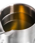 Close-up of Kickback Ready 18 Oz Stainless Steel Cocktail Mixing Glass with liquid, showcasing the weighted base and spout design.
