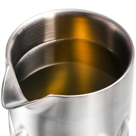 Close-up of Kickback Ready 18 Oz Stainless Steel Cocktail Mixing Glass with liquid, showcasing the weighted base and spout design.