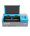 OMTech K40+ 45W CO2 laser engraver, desktop 12x8 in, blue-gray housing with open lid and control panel.
