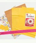 Iron-On Adhesive For Fabrics, Seven Eighths Inch By 10 Yards with yellow fabric, zipper, and floral cloth, for home decor use.