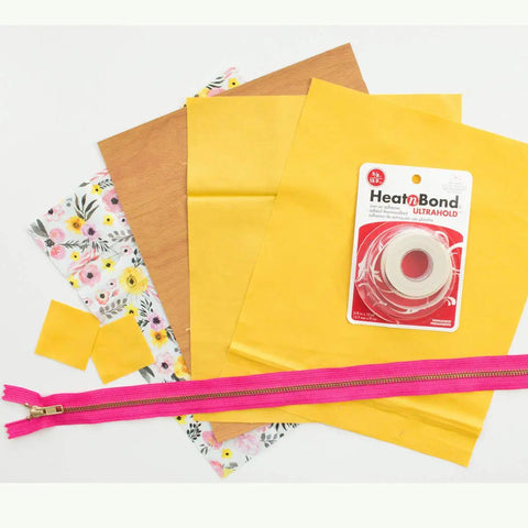 Iron-On Adhesive For Fabrics, Seven Eighths Inch By 10 Yards with yellow fabric, zipper, and floral cloth, for home decor use.