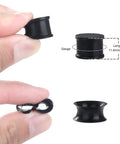 Hand holding black Silicone Ear Plugs Gauge Stretching Kit for Ear Piercings and Lobe Stretchers, 32 Pieces, 11.4mm length.