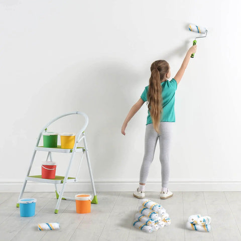 Child using Bulk Pack 100 Mini Paint Roller Covers 6 Inch For Quick Home Painting DIY Projects on white wall, with ladder and paints