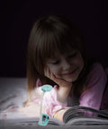 Child reading with Kids Clip On Reading Light 3 Pack Battery Operated Dimmable Lamp, flexible neck, kid-friendly design.