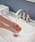 Hamden Spot Resist Brushed Nickel Two Handle 4 Inch Centerset Bathroom Faucet with water flowing onto hands in sink