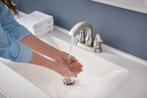 Hamden Spot Resist Brushed Nickel Two Handle 4 Inch Centerset Bathroom Faucet with water flowing onto hands in sink