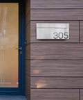 Modern Wall Mounted Home Mailbox In Stainless Steel Rust Resistant Weatherproof on wooden panel wall next to a door