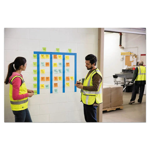 Workers using Extreme Adhesive Orange Sticky Notes 3x3 Inches For Rugged Jobsites on wall board in factory setting.