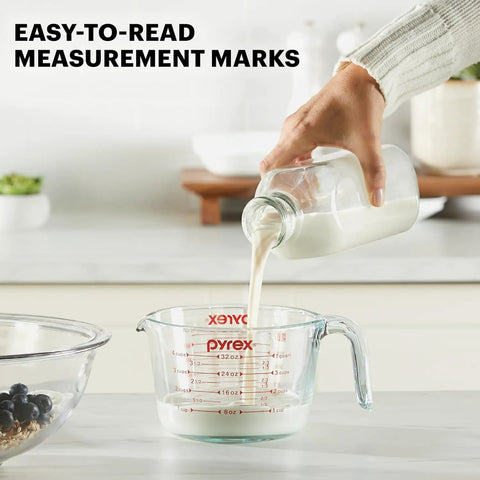 Pouring milk into Two Piece Glass Measuring Cups Set With 1 Cup And 2 Cup Sizes For Easy No Fuss Prep Baking And Cooking Oven Safe Microwave Safe Freezer Safe And Dishwasher Safe Clear Ounces And Milliliters Measurements For Fast Pouring.
