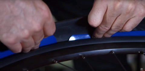 Hands installing Z-Liner Rim Tape Pair for 26, 27.5, and 29 Inch Wheels, 50mm Wide Purple Protective Barrier Between Inner Tube and Tire.