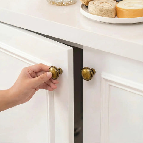 Person using Vintage Antique Brass Cabinet Knobs And Drawer Handles 1 1/4 Inch on white cabinets.