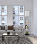 Versailles Floor Lamp With Built-In Shelves, 57.5 Inch Matte Black, White Linen Shade next to white sofa in bright living room.