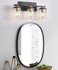 3-Light Black And Gold Bathroom Vanity Lights With Glass Cylinder Sconces For Wall Mounted Bathroom Lighting above mirror.
