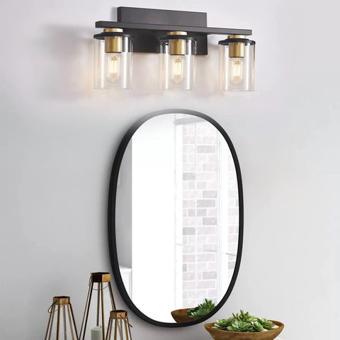 3-Light Black And Gold Bathroom Vanity Lights With Glass Cylinder Sconces For Wall Mounted Bathroom Lighting above mirror.