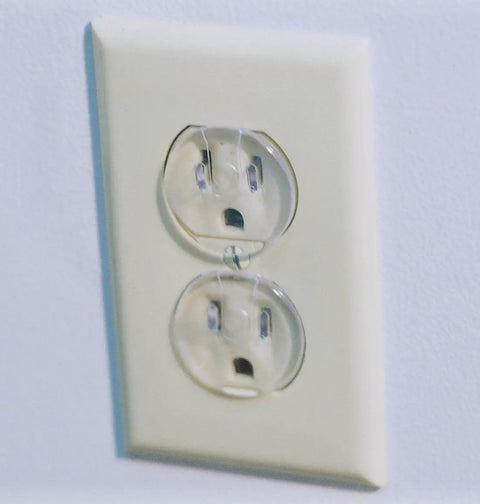 Super Stealthy Child Proof Outlet Covers 12 Pack Ultra Clear Plastic Electrical Safety Plugs Removable Reusable close-up of childproof outlet cover in white wall socket.