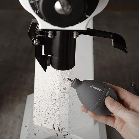 Hand using Air Blower Dust Cleaner Tool For Coffee Grinders Cameras Keyboards And Watches With Silicone Body And Stainless Steel Nozzle