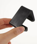 Hand holding a single black clip from the 12 Pack Patio Furniture Clips For Outdoor Rattan Wicker Sofas And Sectionals, No Slip Couch Clips