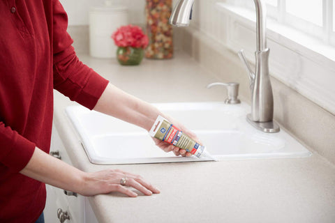 Advanced Silicone Kitchen And Bath Sealant In Almond Color For Easy DIY No Mess Caulking In Kitchens And Bathrooms Two Point Eight Ounce Tube Made In USA Durable Long Lasting Grout Line Edge Sealant used on a kitchen sink countertop.