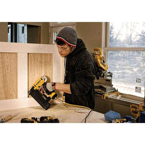 Professional 18 Gauge Brad Nailer With Rear Exhaust Blasts Dust Away Tight Trigger used by a carpenter assembling wood panels.