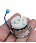 Close-up of miniature DC 24V electromagnetic clutch with white plastic rotor, metal housing, and blue wire lead.
