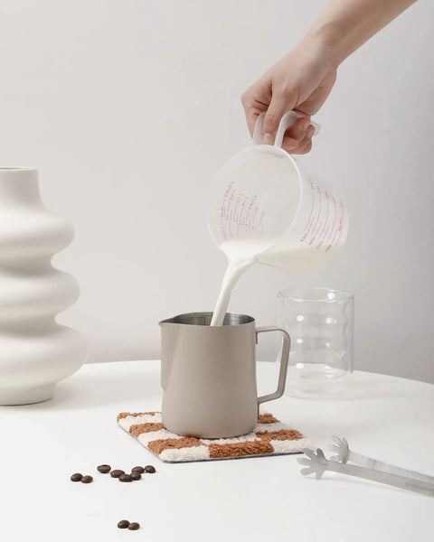 Stainless Steel Milk Frothing Pitcher With 14oz And 20oz Capacity For Latte Art on a table, milk being poured in, barista grade